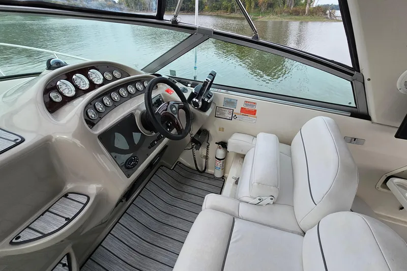 Slide: The Image of 2004 Monterey 282 Cruiser helm with gauges, steering wheel, and white seating on a calm lake. - 9