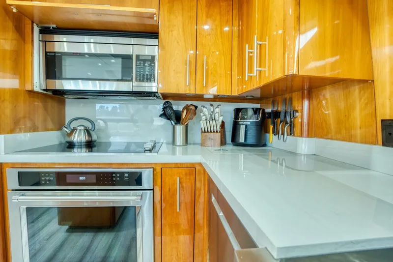 Slide: The Image of Modern kitchen in 2007 Hatteras 80 Enclosed Bridge yacht with wooden cabinets and stainless steel appliances. - 21