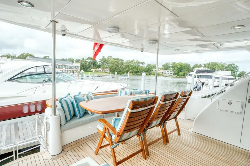 Slide: The Image of Luxury yacht deck with wooden chairs, table, and striped cushions; 2007 Hatteras 80 Enclosed Bridge. - 4