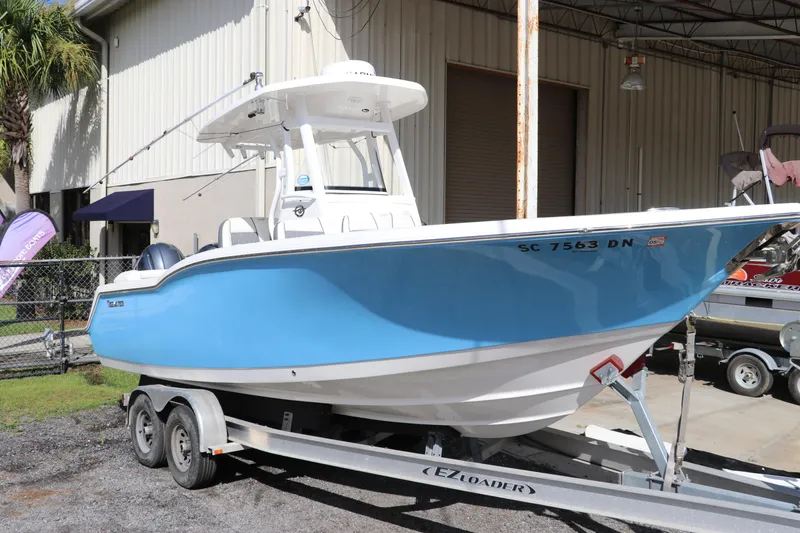 The Image of 2020 Tidewater 252 LXF boat on trailer, blue hull, parked outside a warehouse. - 0