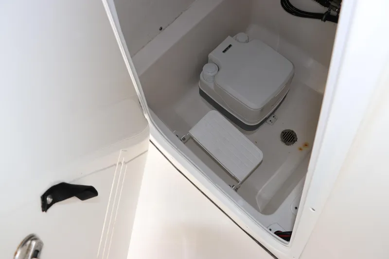 Slide: The Image of 2020 Tidewater 252 LXF boat interior compartment with portable toilet and drainage system. - 40