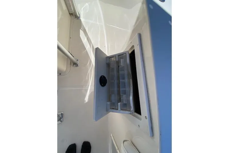 Slide: The Image of 2004 Sea Hunt Triton 220 boat storage compartment with open lid and visible tackle box. - 11
