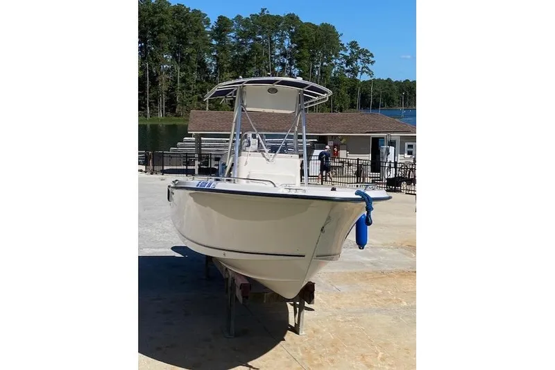 Slide: The Image of 2004 Sea Hunt Triton 220 boat on a trailer, dockside with trees in the background. - 4