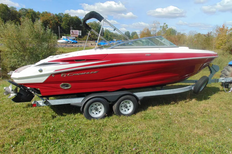 The Image of 2013 Crownline 235 SS boat on trailer, red and white, parked on grass. - 2
