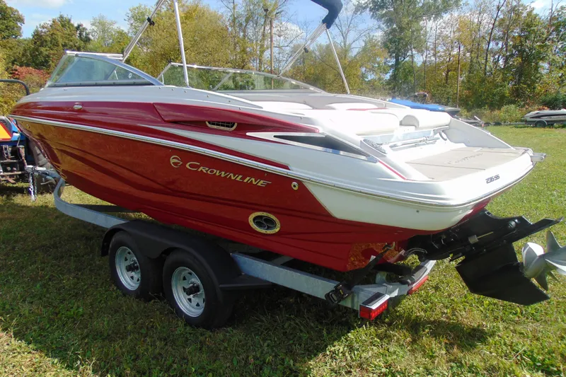 Slide: The Image of 2013 Crownline 235 SS boat on trailer, red and white, parked on grass. - 8