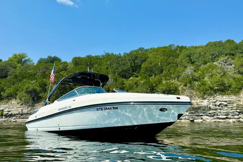 Slide: The Image of 2011 Rinker 276 Captiva boat on water, lush green shoreline background. - 1