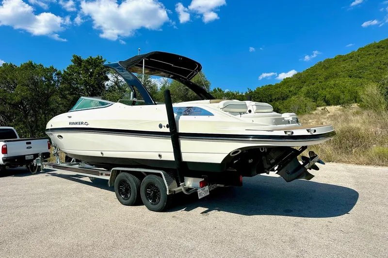 Slide: The Image of 2011 Rinker 276 Captiva boat on trailer, parked outdoors under blue sky. - 10