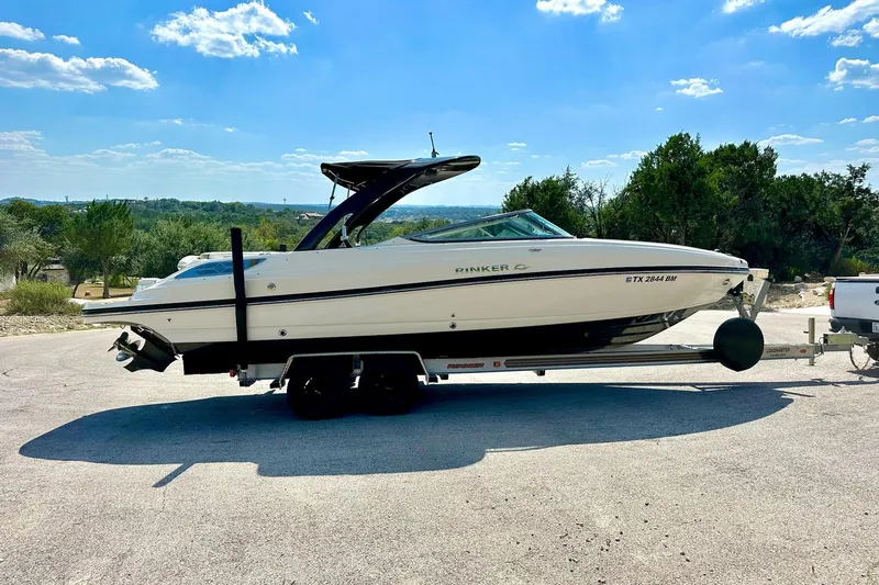 Slide: The Image of 2011 Rinker 276 Captiva boat on trailer, parked outdoors under a clear sky. - 12