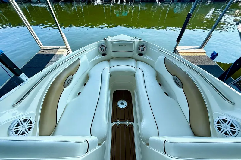 Slide: The Image of 2011 Rinker 276 Captiva boat interior with white and tan seating, docked by the water. - 22