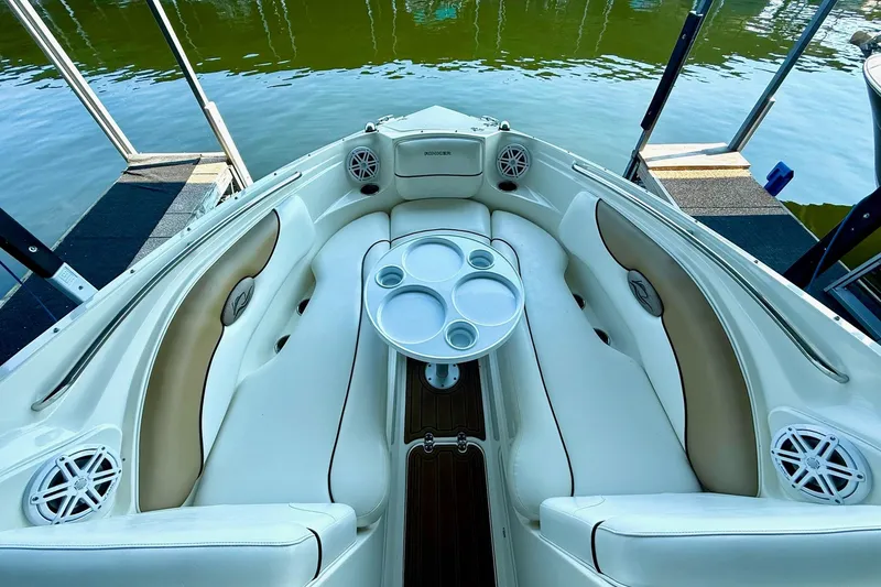 Slide: The Image of 2011 Rinker 276 Captiva boat interior with white seating and cup holders by the water. - 23