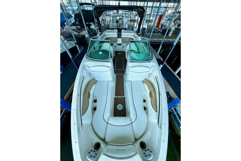 Slide: The Image of 2011 Rinker 276 Captiva boat interior with white seating and wood accents in a marina. - 24