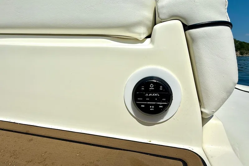Slide: The Image of JL Audio control panel on 2011 Rinker 276 Captiva boat, beige upholstery, sunny day. - 35
