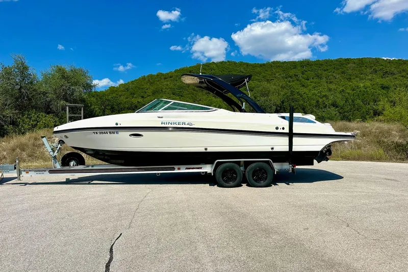 Slide: The Image of 2011 Rinker 276 Captiva boat on trailer, parked outdoors under blue sky. - 9