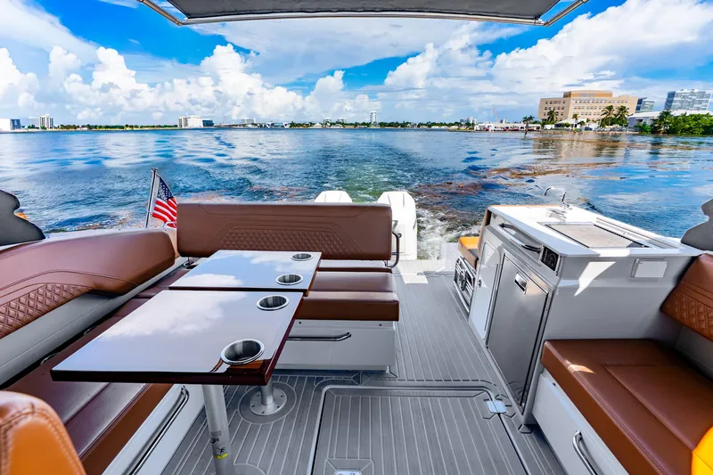 Slide: The Image of 2024 Cruisers Yachts 34 GLS OB interior with seating, table, and kitchenette on open water. - 10