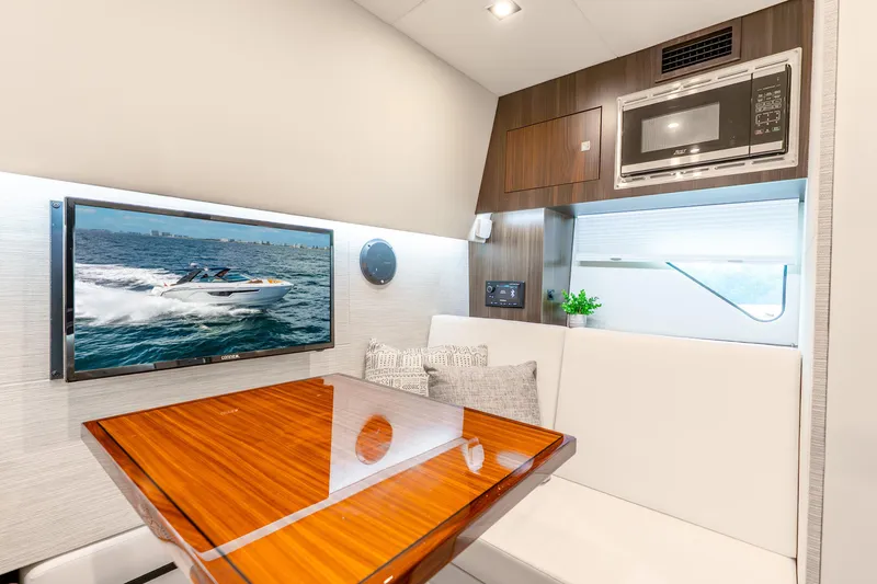 Slide: The Image of 2024 Cruisers Yachts 34 GLS OB interior with TV, microwave, and elegant seating area. - 14