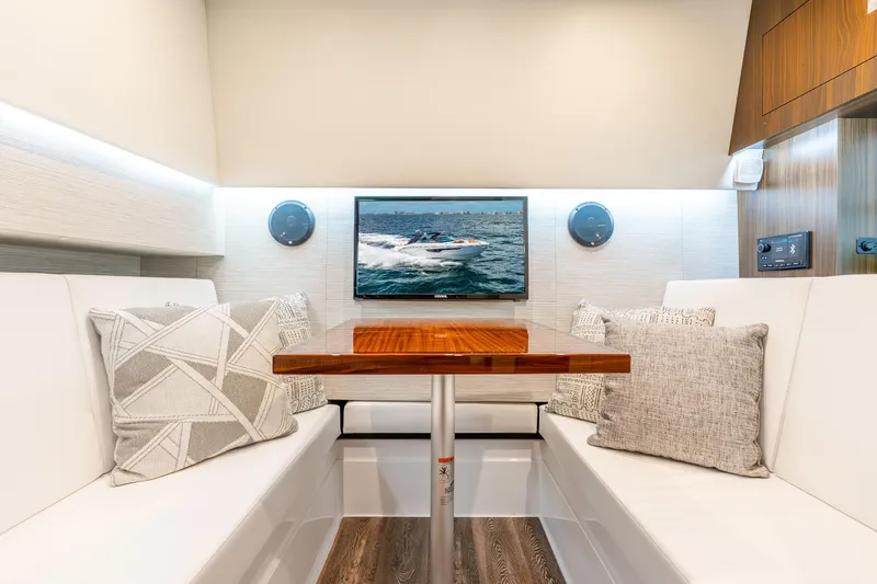 Slide: The Image of 2024 Cruisers Yachts 34 GLS OB interior with elegant seating, wooden table, and mounted TV. - 15