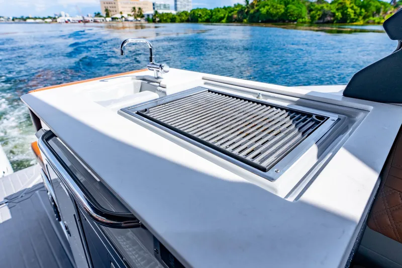 Slide: The Image of Outdoor kitchen on 2024 Cruisers Yachts 34 GLS OB, featuring a grill and sink by the water. - 23
