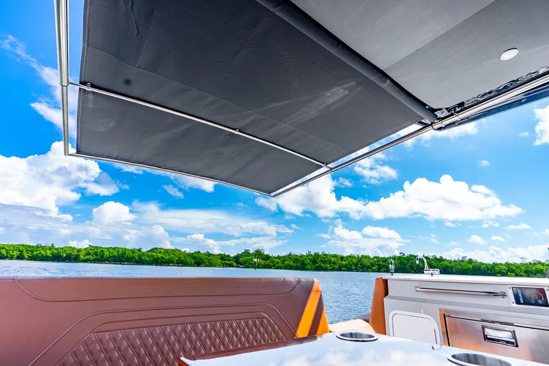 Slide: The Image of 2024 Cruisers Yachts 34 GLS OB interior with canopy, overlooking serene water and lush greenery. - 29