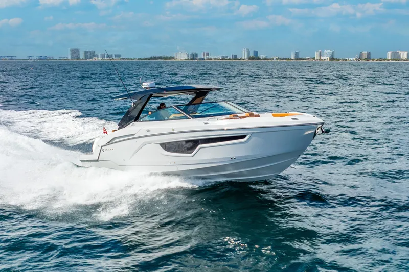 Slide: The Image of 2024 Cruisers Yachts 34 GLS OB cruising on open water, city skyline in background. - 7