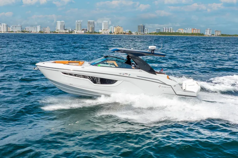 Slide: The Image of 2024 Cruisers Yachts 34 GLS OB cruising on ocean with city skyline in background. - 8