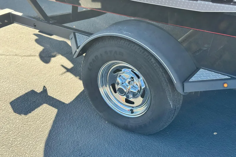 Slide: The Image of 2019 Tracker Pro Team 175 trailer wheel with chrome hubcap on asphalt. - 20