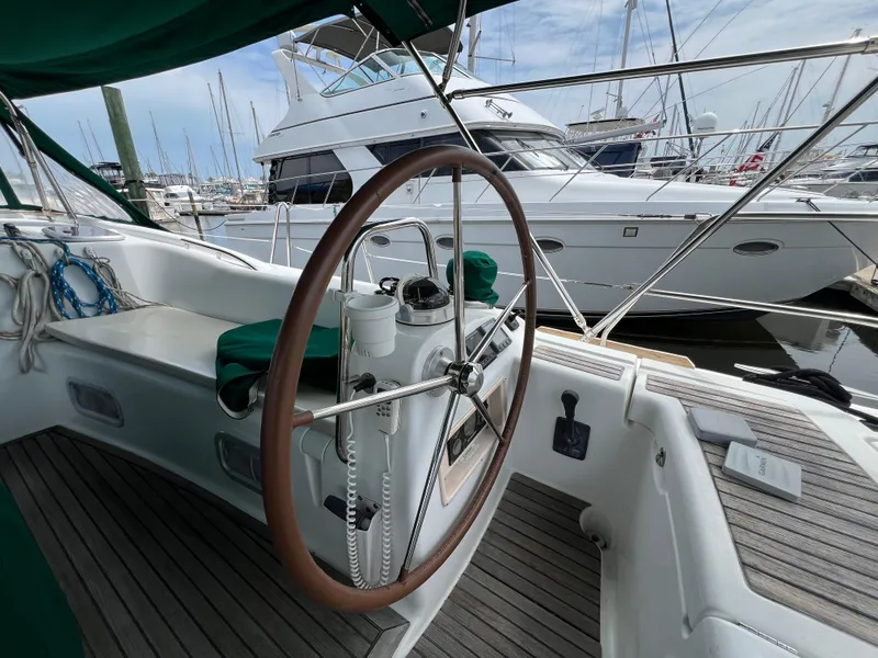 Slide: The Image of 2007 Beneteau Oceanis 46 sailboat cockpit with wooden steering wheel, docked in marina. - 43