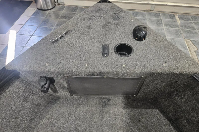 Slide: The Image of 2014 Lund 1650 Rebel XL Sport boat interior with carpeted deck and storage compartments. - 17