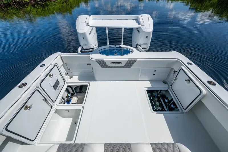 Slide: The Image of 2025 Invincible 33 Catamaran deck with open storage compartments and twin Mercury engines. - 15