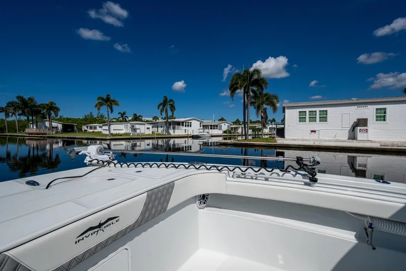 Slide: The Image of 2025 Invincible 33 Catamaran docked by palm trees and waterfront homes under clear blue sky. - 20