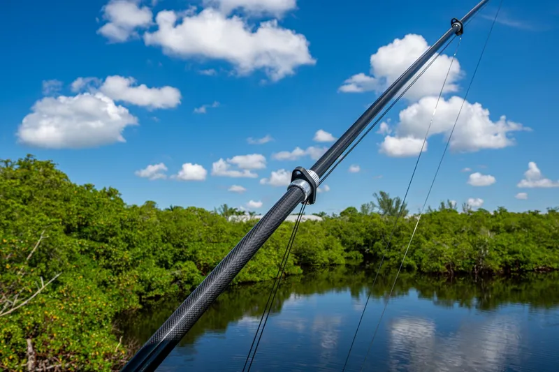 Slide: The Image of Fishing rod over serene water and lush greenery, clear blue sky, Invincible 33 Catamaran 2025. - 24