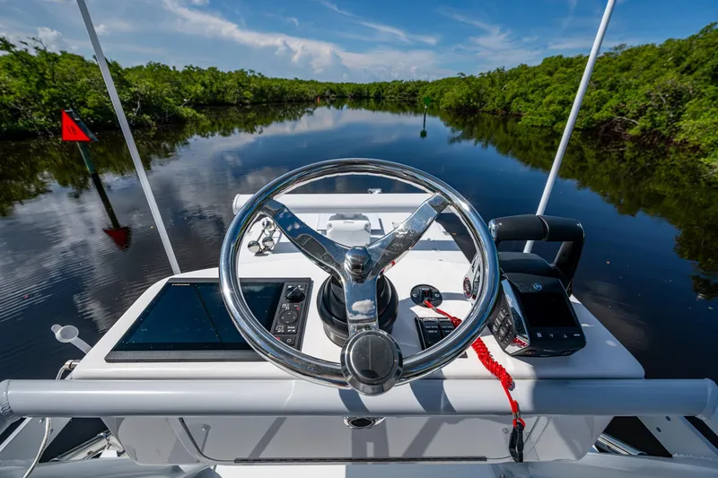 Slide: The Image of Steering console of 2025 Invincible 33 Catamaran on a serene waterway. - 25