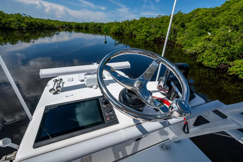 Slide: The Image of 2025 Invincible 33 Catamaran helm with steering wheel and navigation system on calm water. - 26