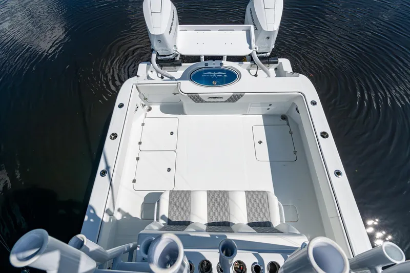 Slide: The Image of 2025 Invincible 33 Catamaran boat deck with dual engines and seating, on calm water. - 31