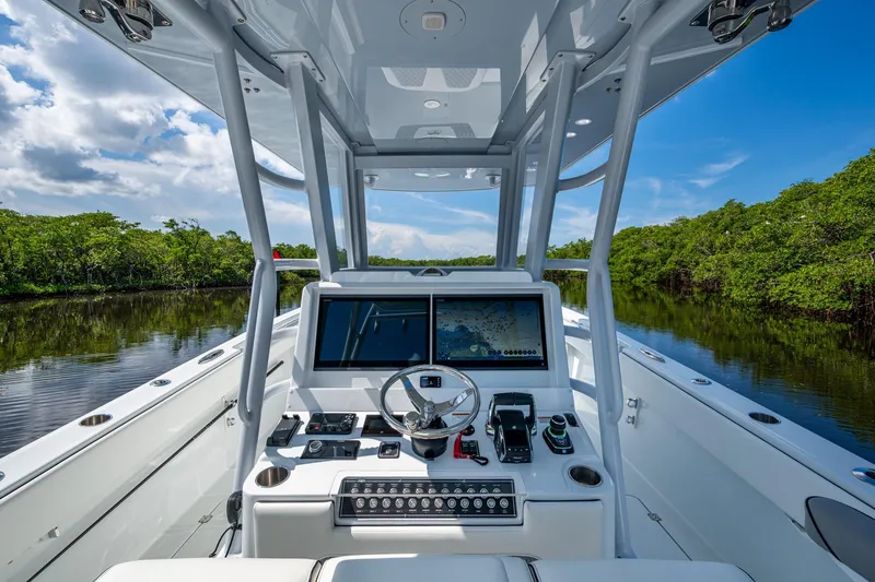 Slide: The Image of 2025 Invincible 33 Catamaran cockpit with advanced navigation system, cruising through lush waterways. - 6