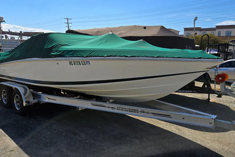 Slide: The Image of 1996 Cobalt 220 boat with green cover on trailer, parked outdoors. - 1