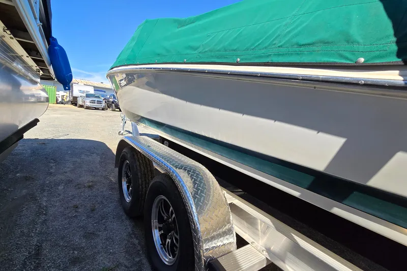 Slide: The Image of 1996 Cobalt 220 boat with green cover on a trailer, parked outdoors. - 10