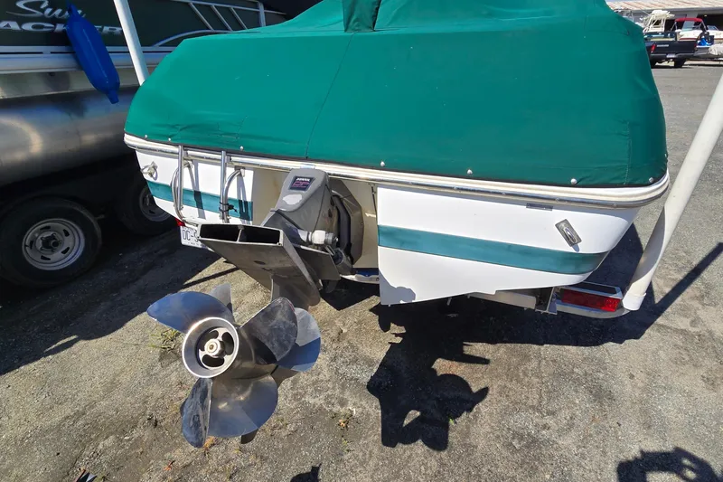 Slide: The Image of 1996 Cobalt 220 boat with green cover and visible propeller in a marina setting. - 9