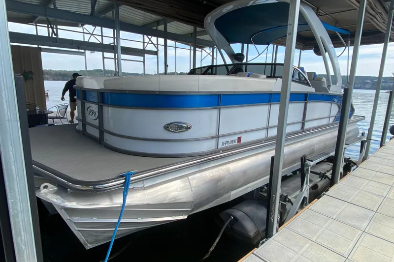 Slide: The Image of 2018 Manitou 25 X-Plode SRW SHP pontoon boat docked in a covered marina. - 10