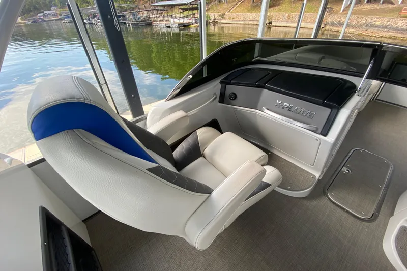 Slide: The Image of Interior of 2018 Manitou 25 X-Plode SRW SHP boat with captain's chair and dashboard. - 21