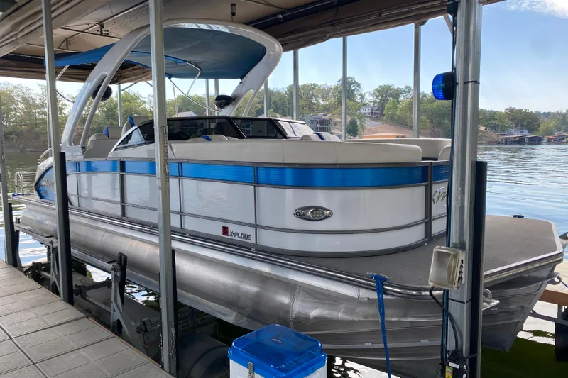 Slide: The Image of 2018 Manitou 25 X-Plode SRW SHP pontoon boat docked on a serene lake. - 8