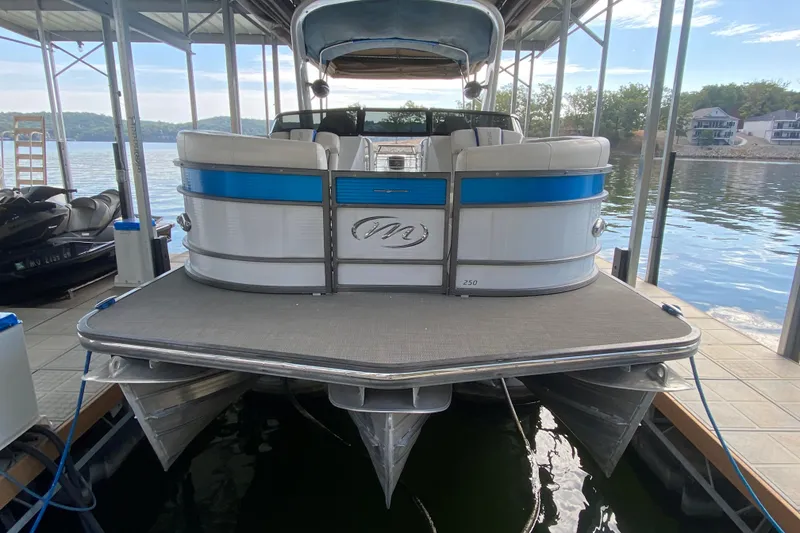 Slide: The Image of 2018 Manitou 25 X-Plode SRW SHP pontoon boat docked on a serene lake. - 9