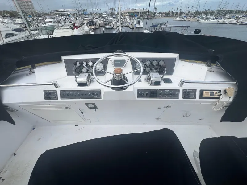 Slide: The Image of 1990 Pace 42 Motor Yacht helm with steering wheel, gauges, and marina view. - 10