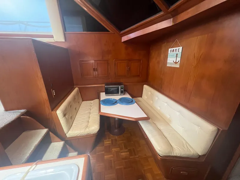 Slide: The Image of 1990 Pace 42 Motor Yacht interior with cozy dining area and wood paneling. - 23