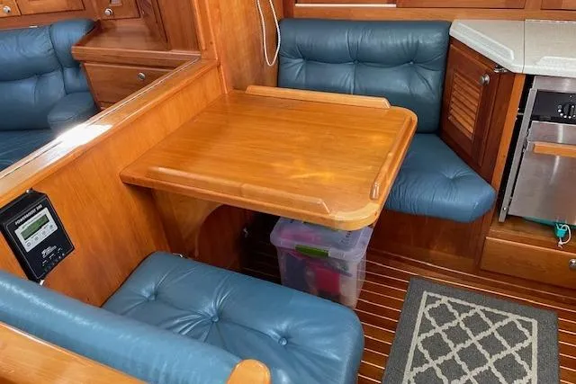 Slide: The Image of Cozy interior of 2000 Gozzard 37 sailboat with wooden table and blue cushioned seating. - 25