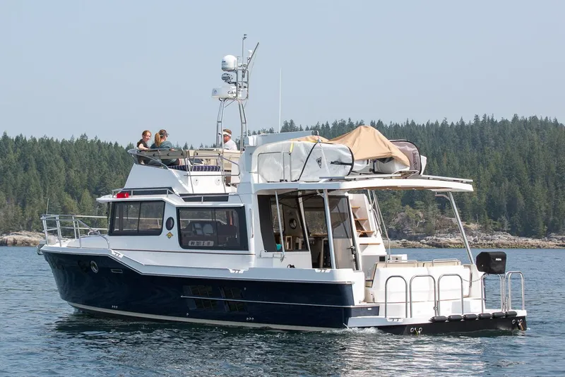 Slide: The Image of Manufacturer Provided Image: 2025 Ranger Tugs R-43 CB cruising on a serene lake with forested shoreline. - 3