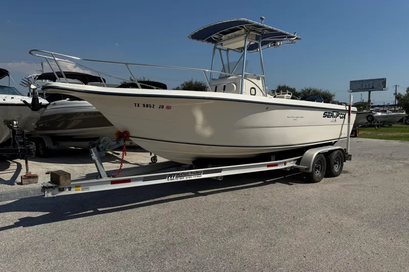 Slide: The Image of 2002 Sea Fox 236 Center Console boat on trailer, parked outdoors under clear sky. - 1
