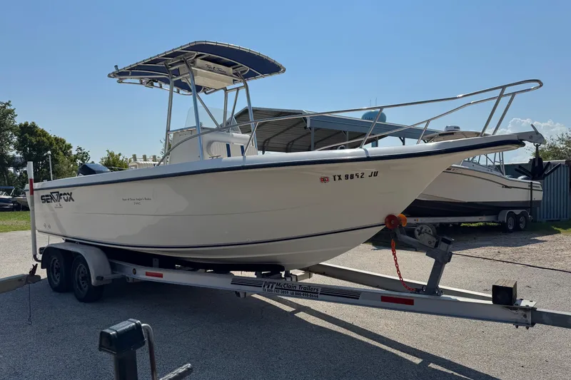 Slide: The Image of 2002 Sea Fox 236 Center Console boat on trailer, parked outdoors under clear sky. - 8