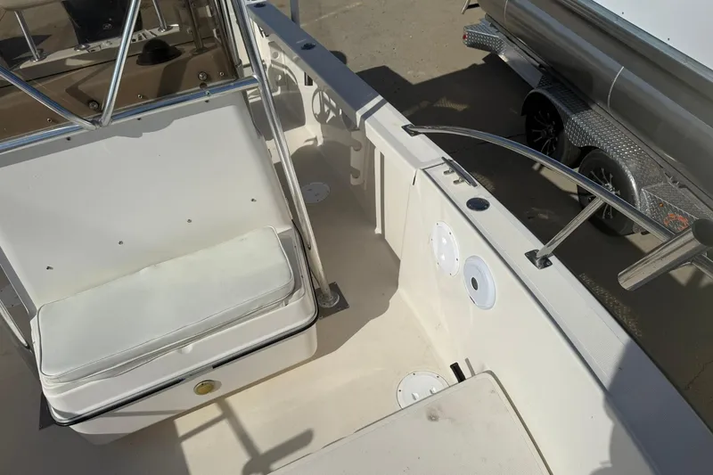 Slide: The Image of 1994 Pursuit 2150 Dual Console boat interior with seating and railing, parked on a trailer. - 25