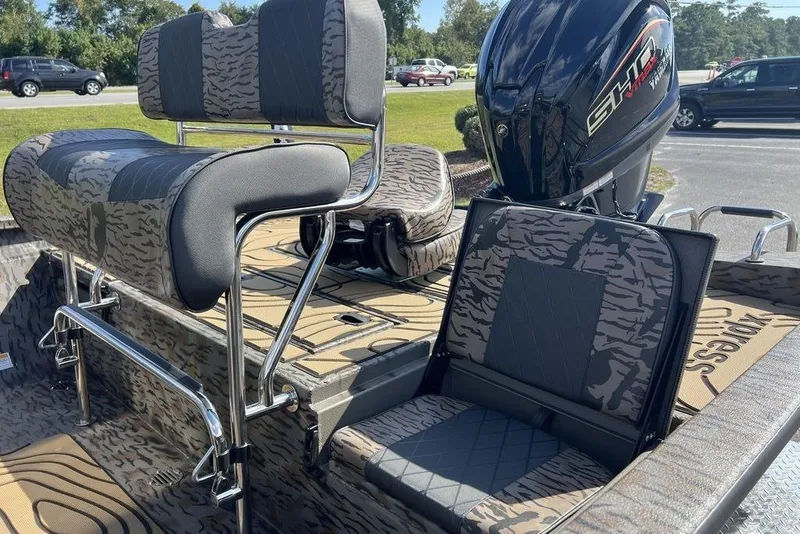 Slide: The Image of 2026 Xpress H22B Bay boat interior with camo seating and powerful outboard motor. - 11