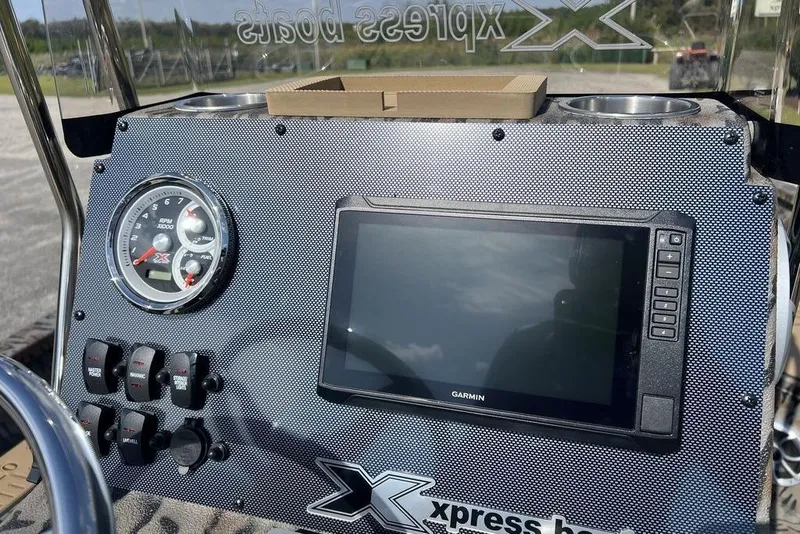 Slide: The Image of 2026 Xpress H22B Bay boat dashboard with Garmin display and control switches. - 15